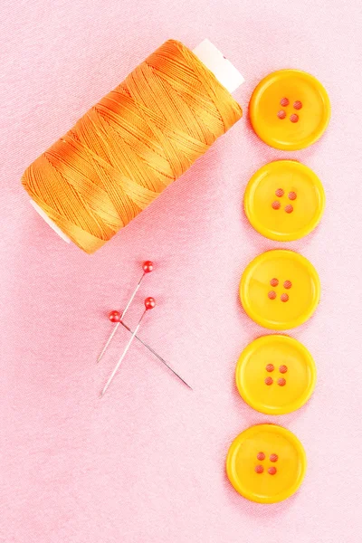 Colorful sewing buttons with thread on pink fabric — Stock Photo, Image