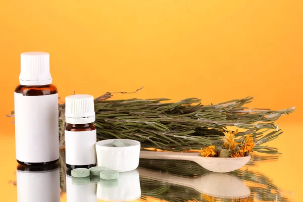 Flaschen mit Medikamenten und Kräutern auf orangefarbenem Hintergrund. Konzept der Homöopathie — Stockfoto