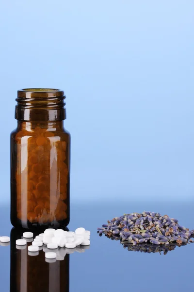 Fles met pillen en kruiden op blauwe achtergrond. concept van de homeopathie — Stockfoto