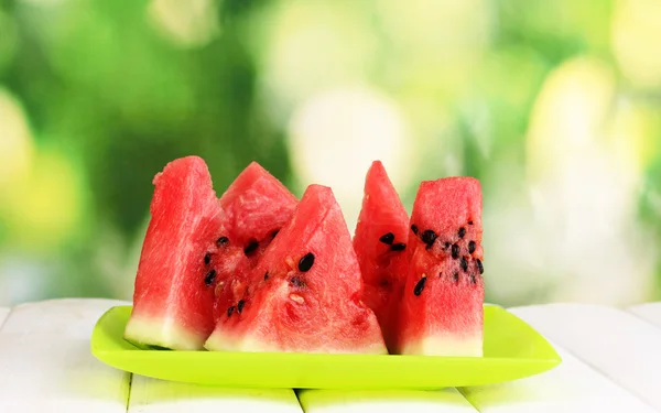 Süße Wassermelonenscheiben auf Teller auf Holztisch vor natürlichem Hintergrund — Stockfoto