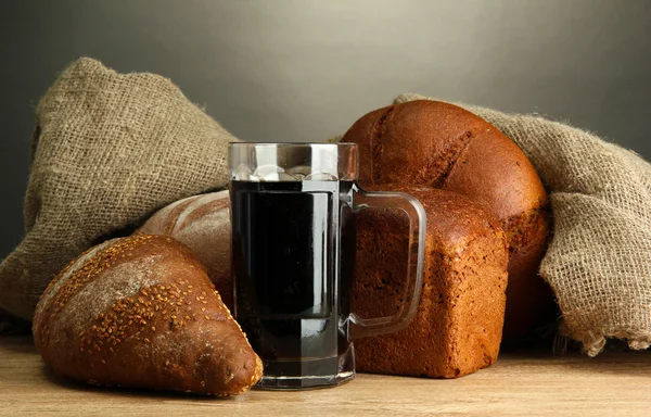 Tankard of kvass and rye breads, on wooden table on grey background — Stock Photo, Image