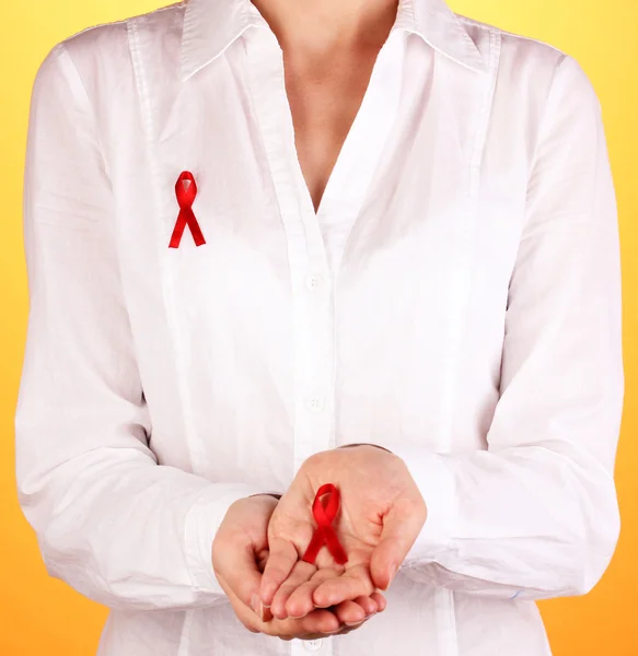 Woman with red ribbon in hands on orange background — Stock Photo, Image