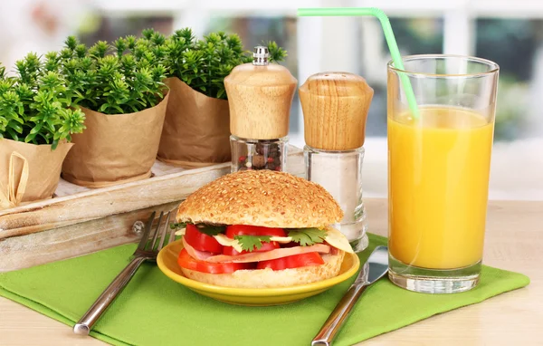 Аппетитный сэндвич на цветовой пластине на деревянном столе на фоне окна — стоковое фото