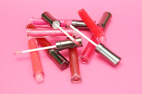 Beautiful lip glosses with rose petals, on pink background — Stock Photo, Image