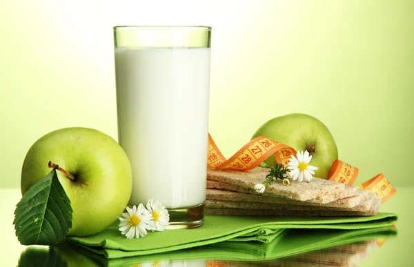 Vaso de kéfir, manzanas, panes fritos y cinta métrica, sobre fondo verde —  Fotos de Stock