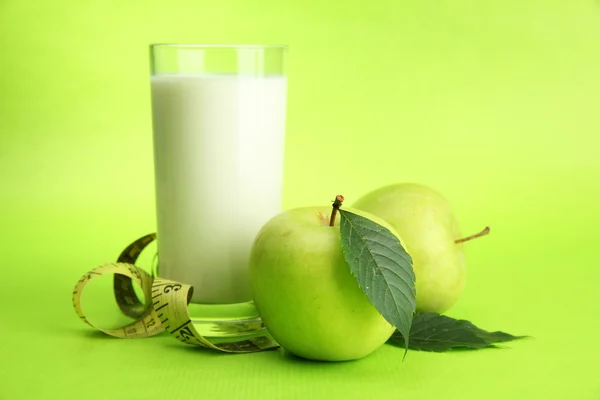 Glas kefir, äpplen och måttband, på grön bakgrund — Stockfoto