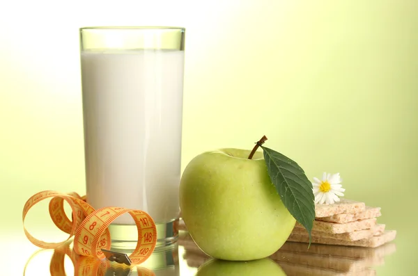 Glas Kefir, Apfel, Knäckebrot und Maßband, auf grünem Hintergrund — Stockfoto