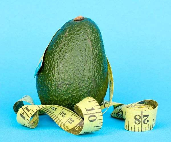 Avocado with measuring tape on blue background — Stock Photo, Image