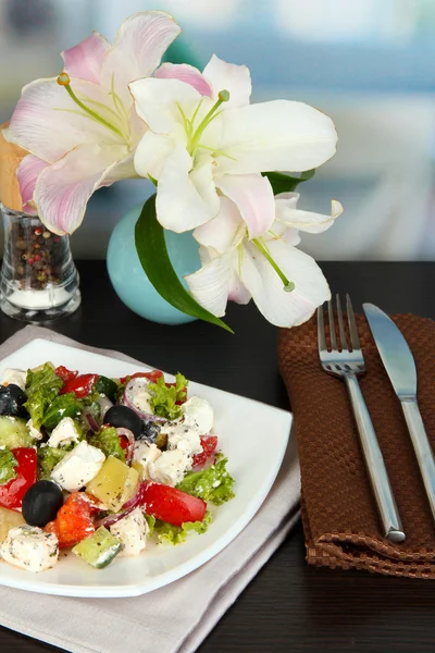 Ensalada griega fresca en plato blanco en la mesa en el fondo del restaurante —  Fotos de Stock