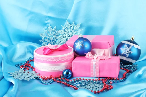 Beautiful pink gifts with blue Christmas balls, snowflakes and beads on blue background — Stok fotoğraf