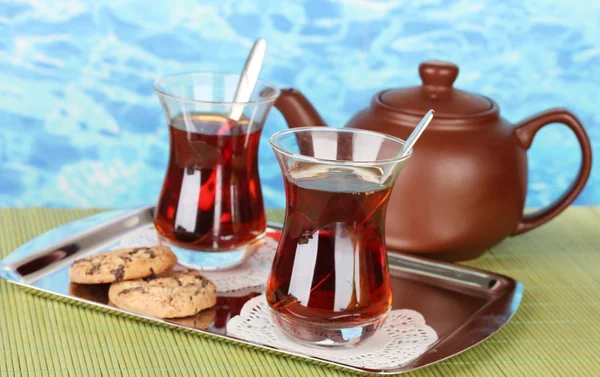 Glass of Turkish tea and kettle on color background — Stock Photo, Image