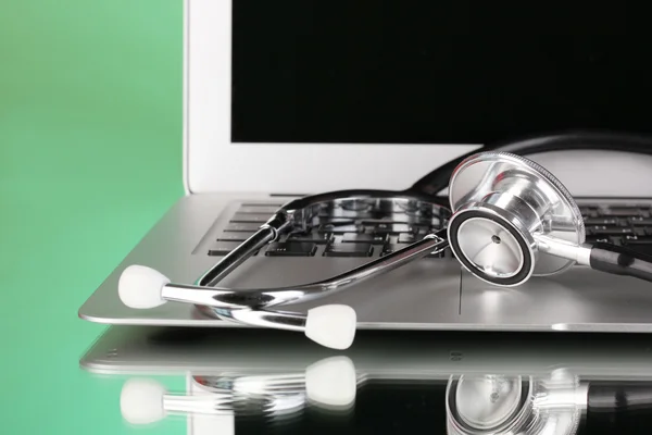 Silver notebook with a stethoscope on green background with reflection close-up — Stock Photo, Image