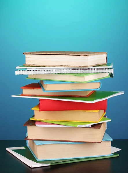 Stapel interessante boeken en de tijdschriften op houten tafel op blauwe achtergrond — Stockfoto