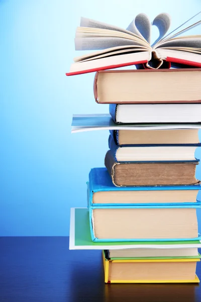 Stapel interessante boeken en de tijdschriften op houten tafel op blauwe achtergrond — Stockfoto