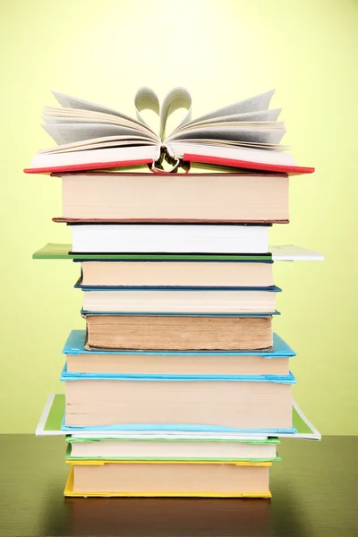 Stapel interessante boeken en de tijdschriften op houten tafel op groene achtergrond — Stockfoto