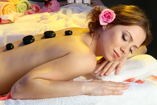 Hermosa mujer joven en el salón de spa con piedras de spa — Foto de Stock