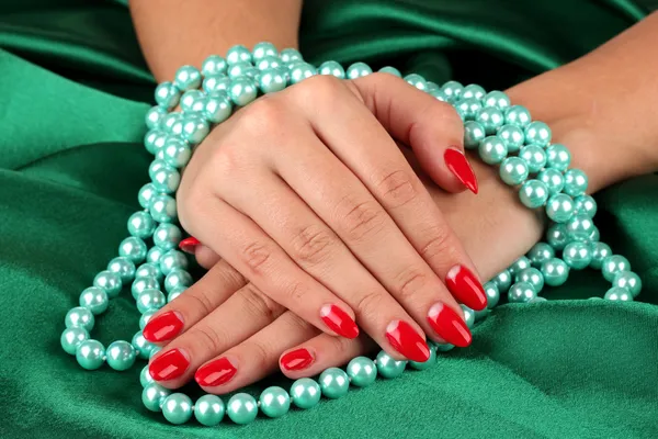 Női kezek gazdaság gyöngyök színes háttérrel — Stock Fotó