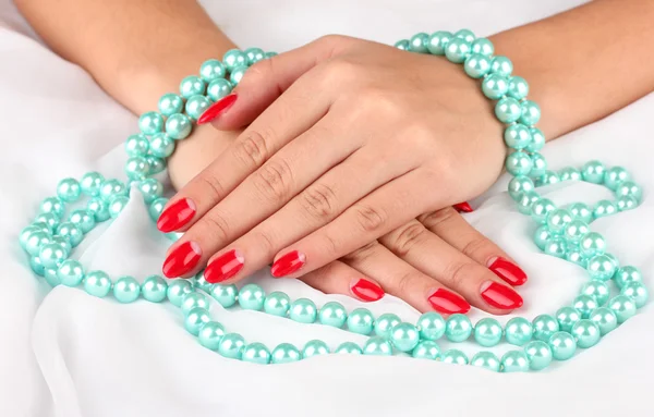 Mains féminines tenant des perles sur fond de couleur — Photo