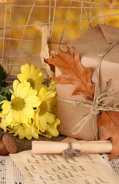 Composição outonal com presente, flores e folhas em fundo brilhante — Fotografia de Stock