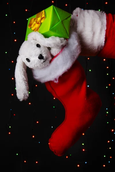 Santa Claus mano sosteniendo regalos sobre fondo brillante — Foto de Stock