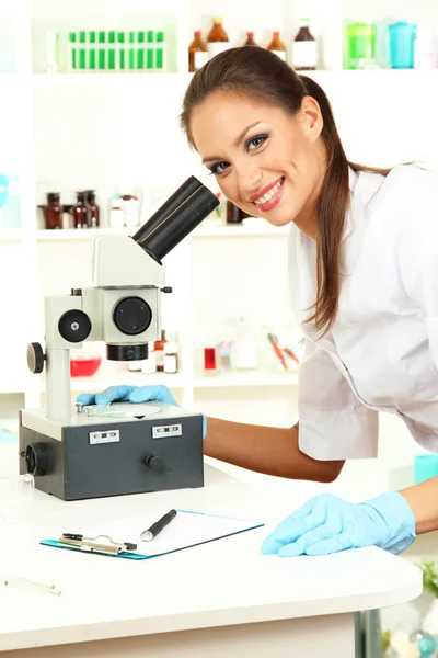 Ilmuwan muda melihat ke dalam mikroskop di laboratorium — Stok Foto