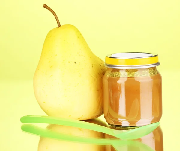 Useful and tasty baby food with pear and spoon on green background — Stock Photo, Image