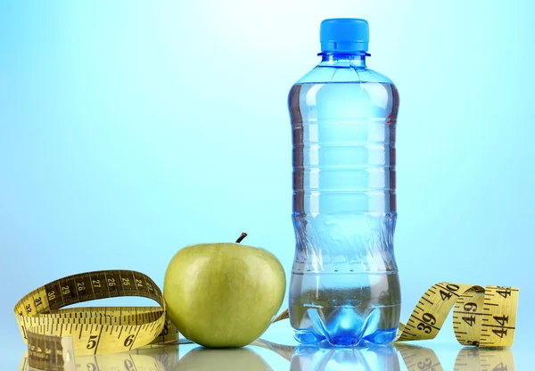 Bottle of water, apple and measuring tape on blue background — Stock Photo, Image