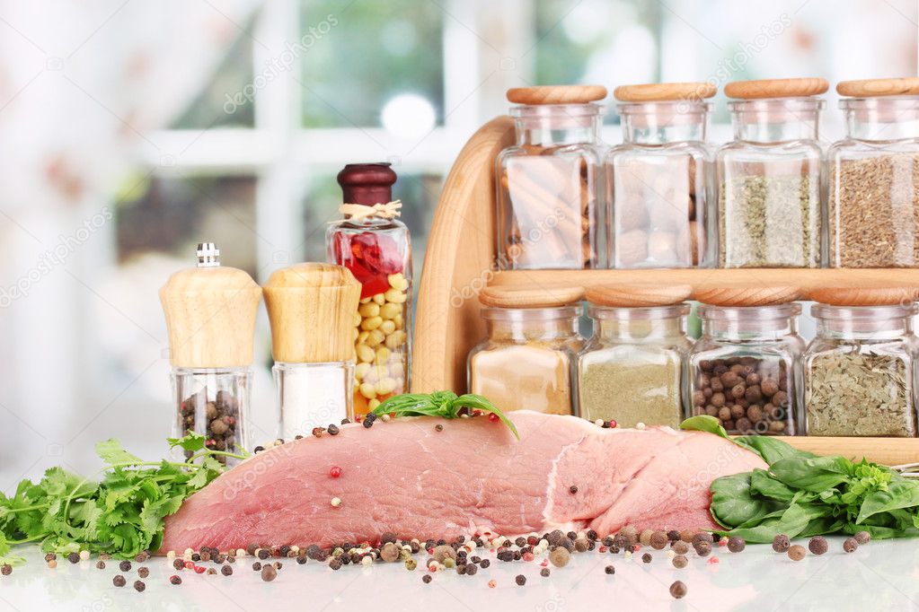 A large piece of pork marinated with herbs and spices on white table on window background