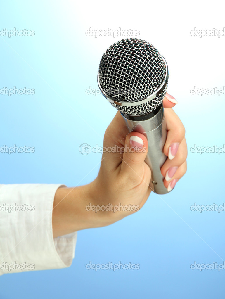 female hand with microphone, on blue background