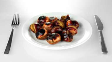 Beyaz tabak çatal ve bıçak üzerinde beyaz izole içinde kavrulmuş kestane