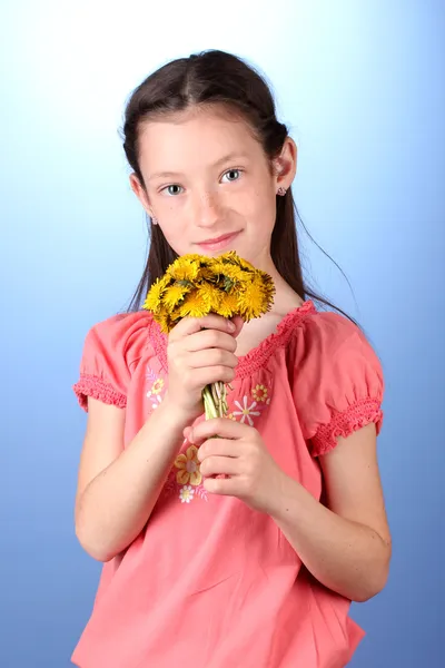Porträt eines schönen kleinen Mädchens mit Löwenzahn auf blauem Hintergrund — Stockfoto