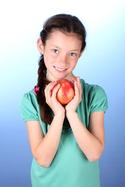 Porträtt av vacker liten flicka med apple på blå bakgrund — Stockfoto
