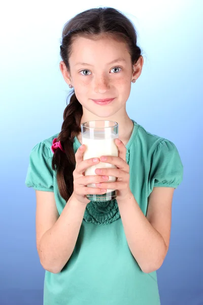 Porträt eines schönen kleinen Mädchens mit Milchglas auf blauem Hintergrund — Stockfoto