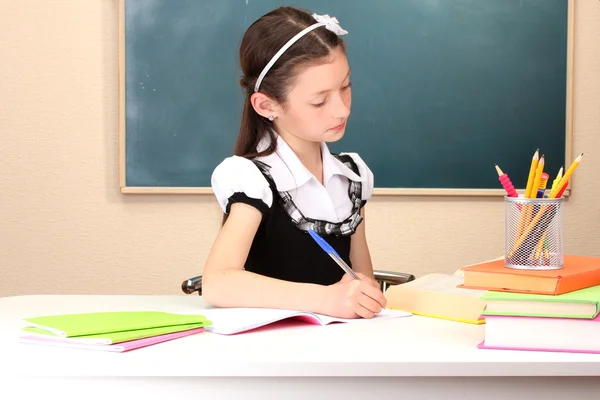 Piccolo scolaro in classe scrivere nel taccuino — Foto Stock