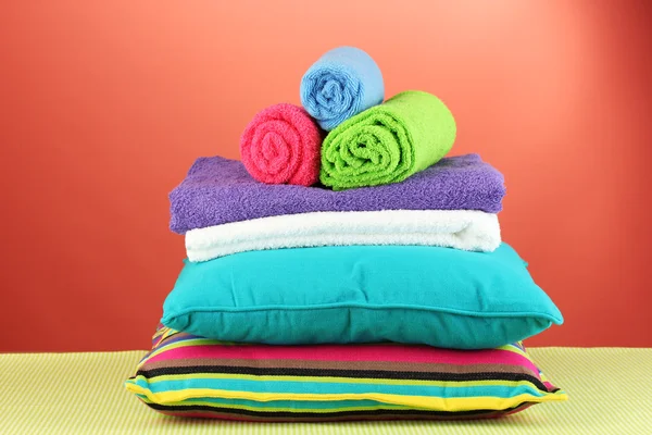 Pillows and towels on red background — Stock Photo, Image