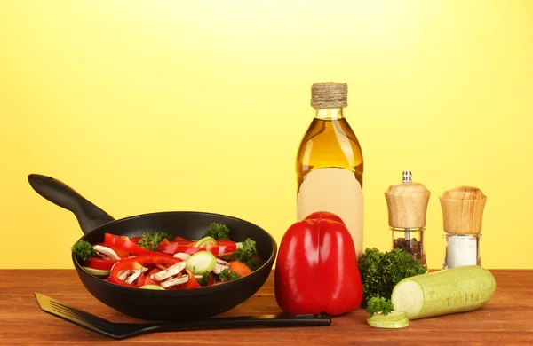 Frigideira com legumes no fundo amarelo — Fotografia de Stock