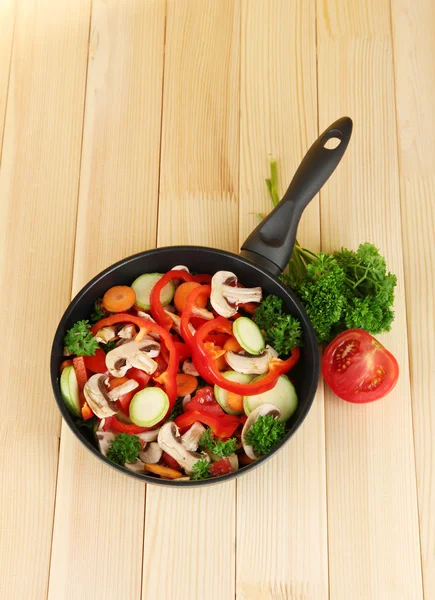 Frying pan with vegetables on wooden background — Stock Photo, Image