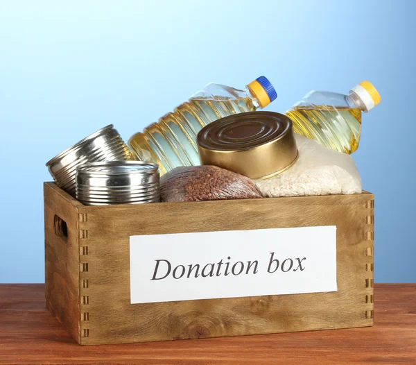 Caja de donaciones con alimentos sobre fondo azul —  Fotos de Stock