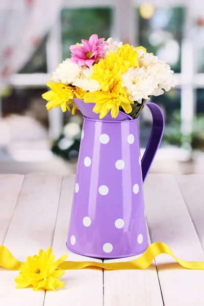 Purple pitcher of peas with flowers on wooden table on window background — Stock Photo, Image