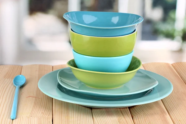 Голубая и зеленая посуда на деревянном столе на фоне окна — стоковое фото