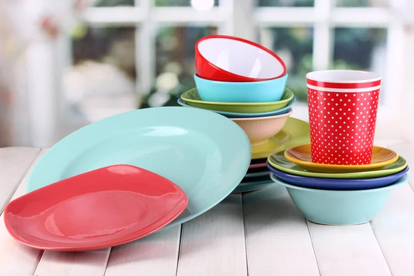 Colorful tableware on wooden table on window background — Stock Photo, Image