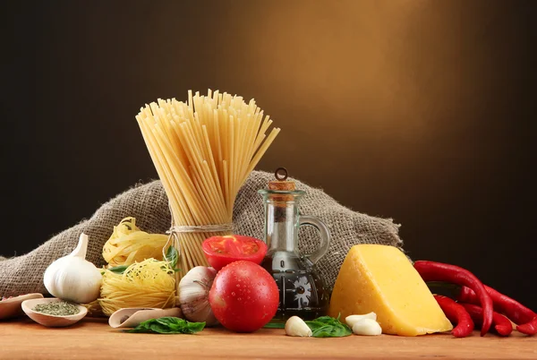 Espaguetis de pasta, verduras y especias, sobre mesa de madera, sobre fondo marrón — Foto de Stock