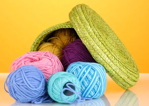 Colorful yarn for knitting in green basket on orange background — Stock Photo, Image