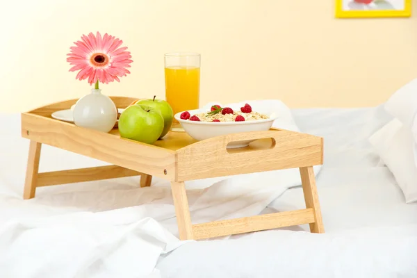 Träbricka med lätt frukost på sängen — Stockfoto