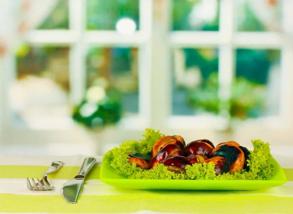 Жареные каштаны с салатом в тарелке на скатерти крупным планом — стоковое фото