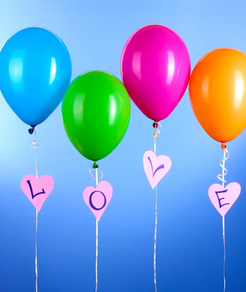 Bunte Luftballons halten Wort Liebe auf blauem Hintergrund — Stockfoto