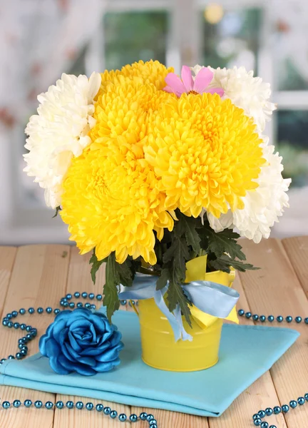 Krásné chryzantémy v vědro na dřevěný stůl na pozadí okna — Stock fotografie