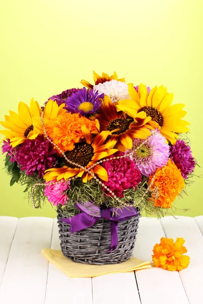 Beautiful bouquet of bright flowers on wooden table on green background — Stock Photo, Image