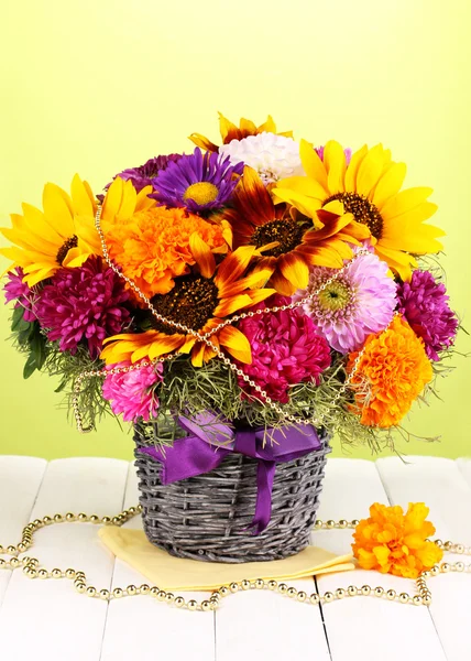 Beautiful bouquet of bright flowers on wooden table on green background — Stock Photo, Image