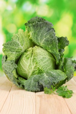 Fresh savoy cabbage on wooden table on natural background